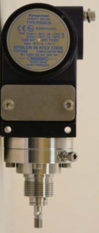 Industrial sensor device with a label, mounted vertically against a light background.